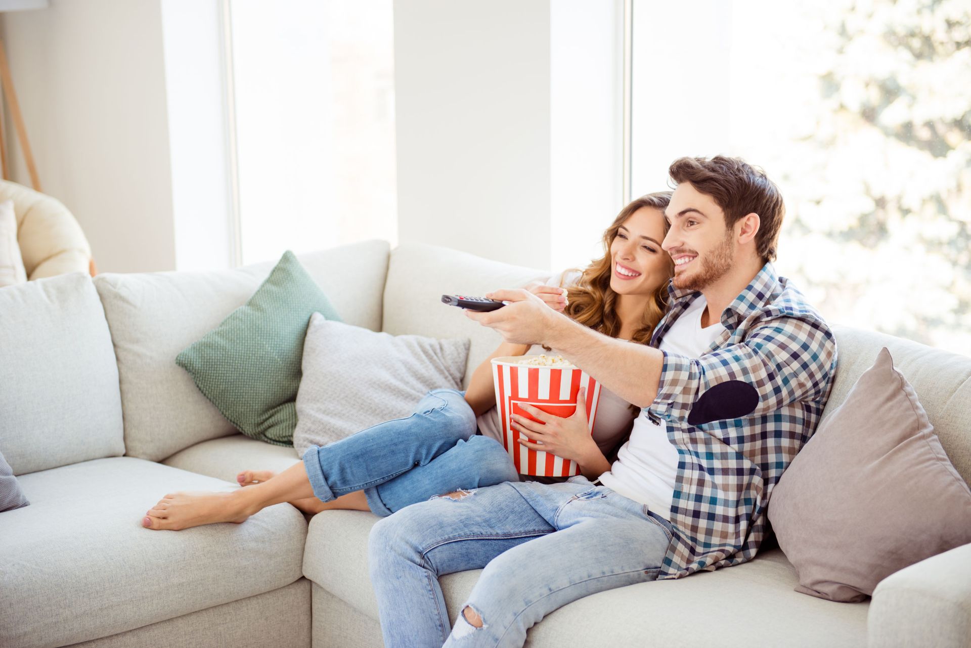 Profile side view of his he her she two person nice attractive charming cheerful guy lady sitting on divan watching new drama comedy in light white style interior living room hotel house indoors.